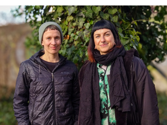 Reg Otters und Anne Hänel nebeneinander und schauen lächelnd in die Kamera